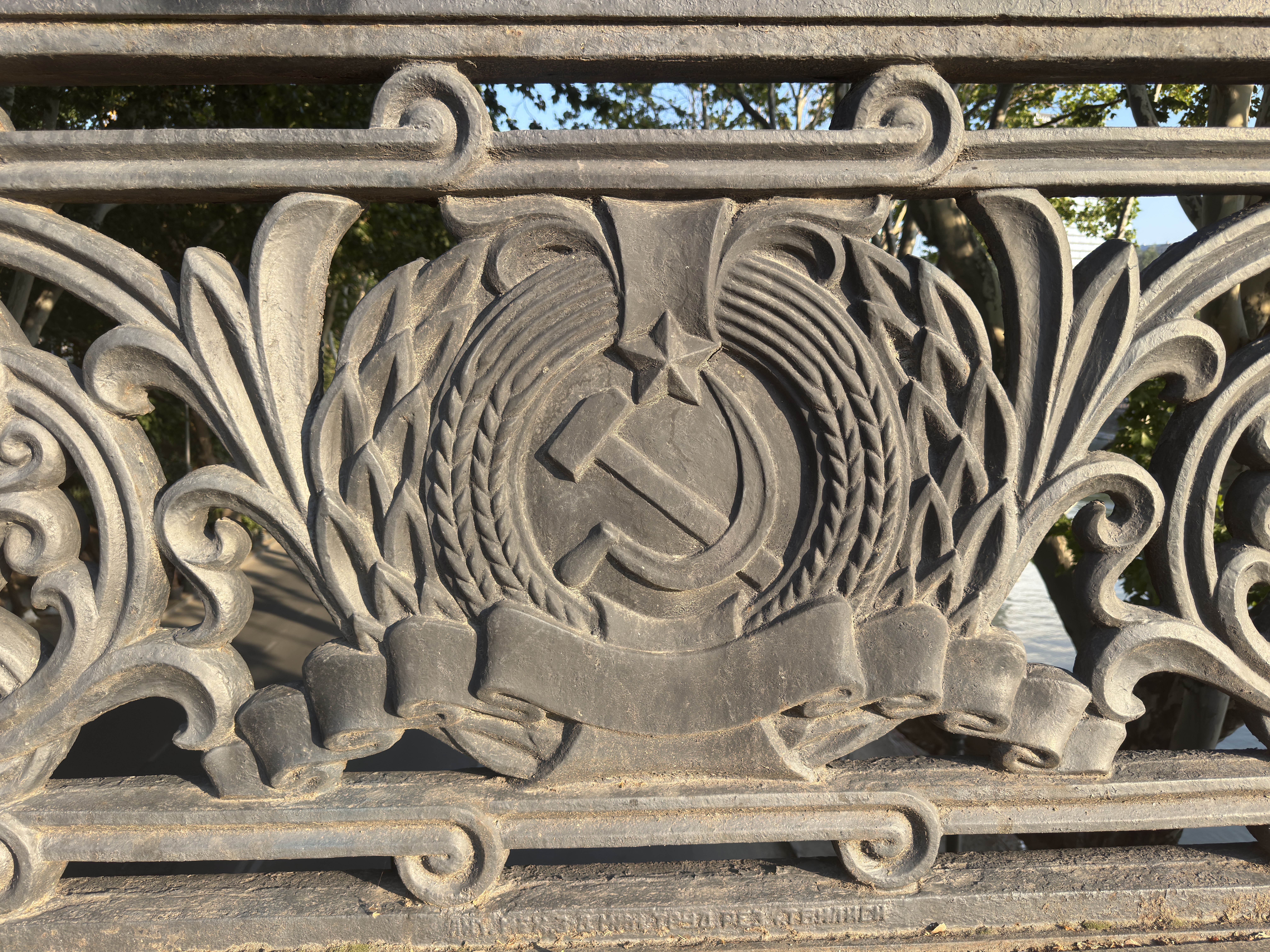Soviet hammer and sickle emblem defaced with spray paint on a bridge railing in Tbilisi, Georgia.